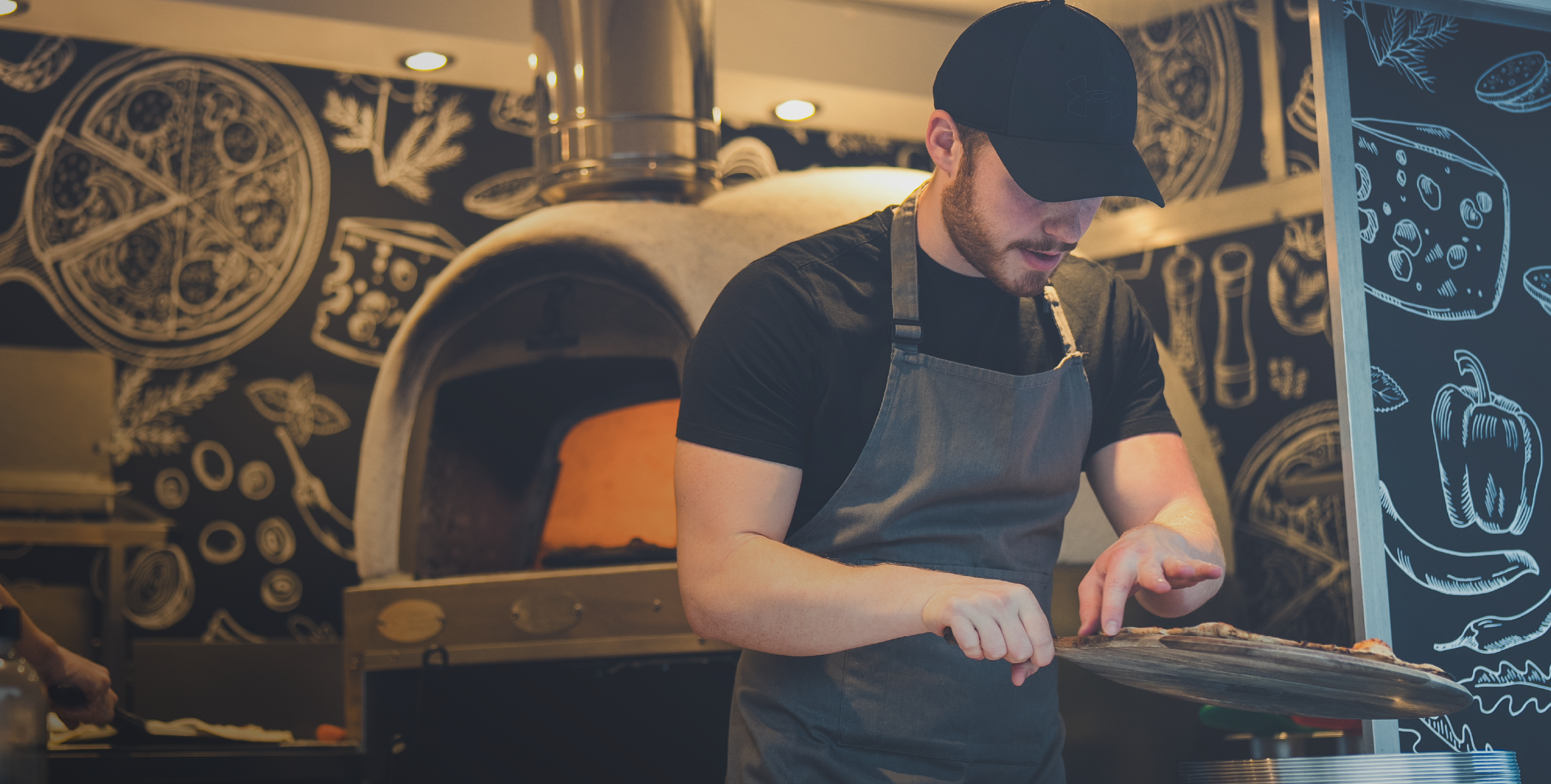 PizzaBox Scotland chef preparing pizza beside a wood fired oven