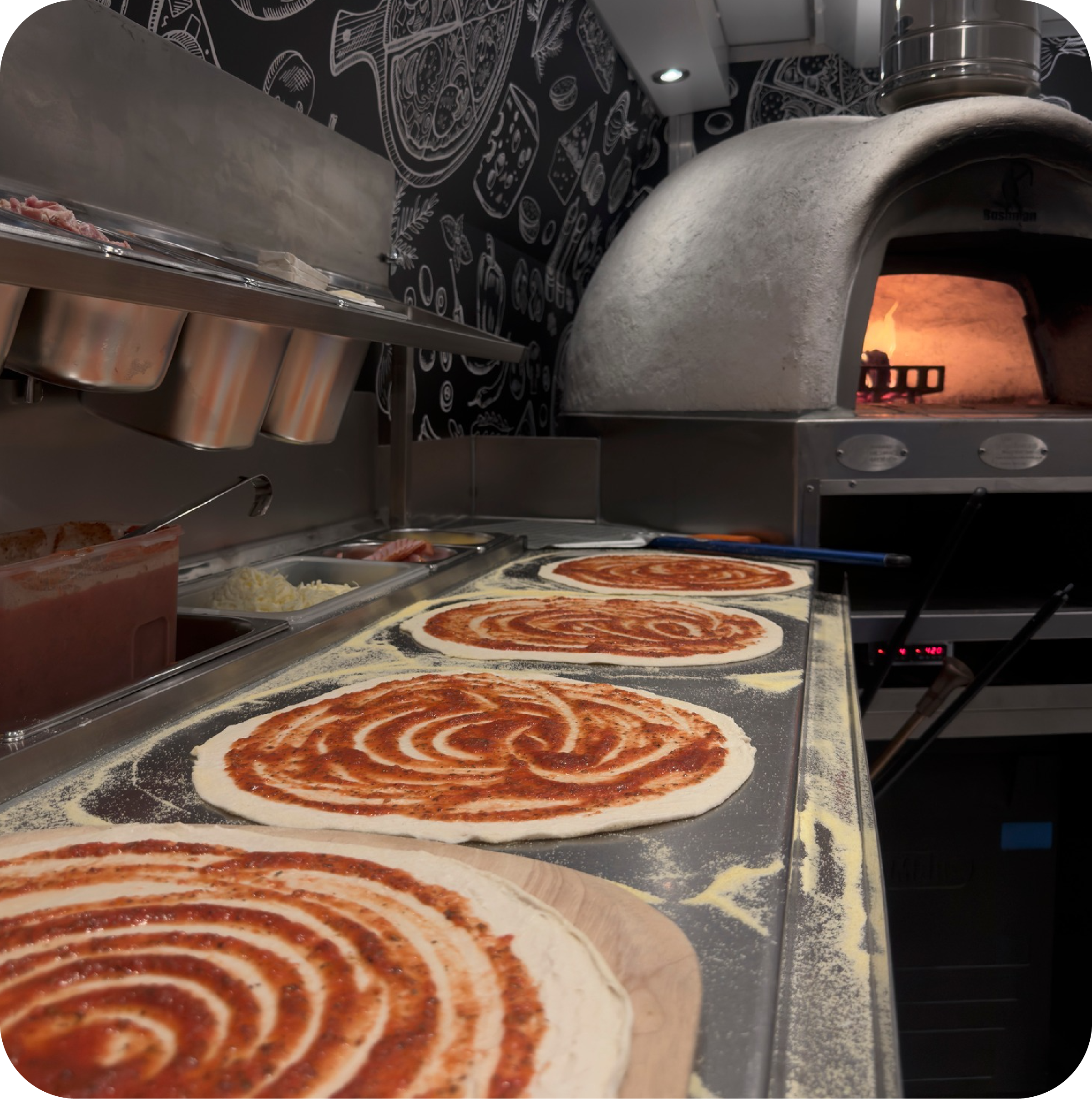 Pizzas being prepared beside the oven